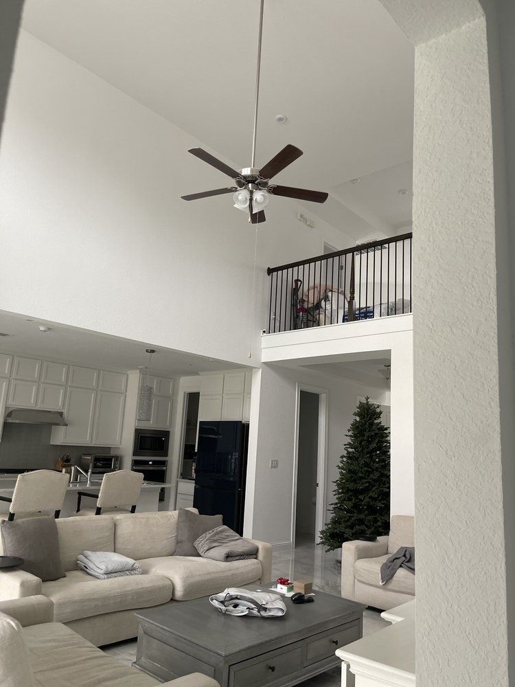Open-concept living area with high ceilings, ceiling fan, and a loft. A couch, chairs, kitchen,