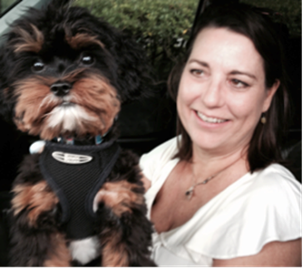 A woman in a white shirt is holding a small dog