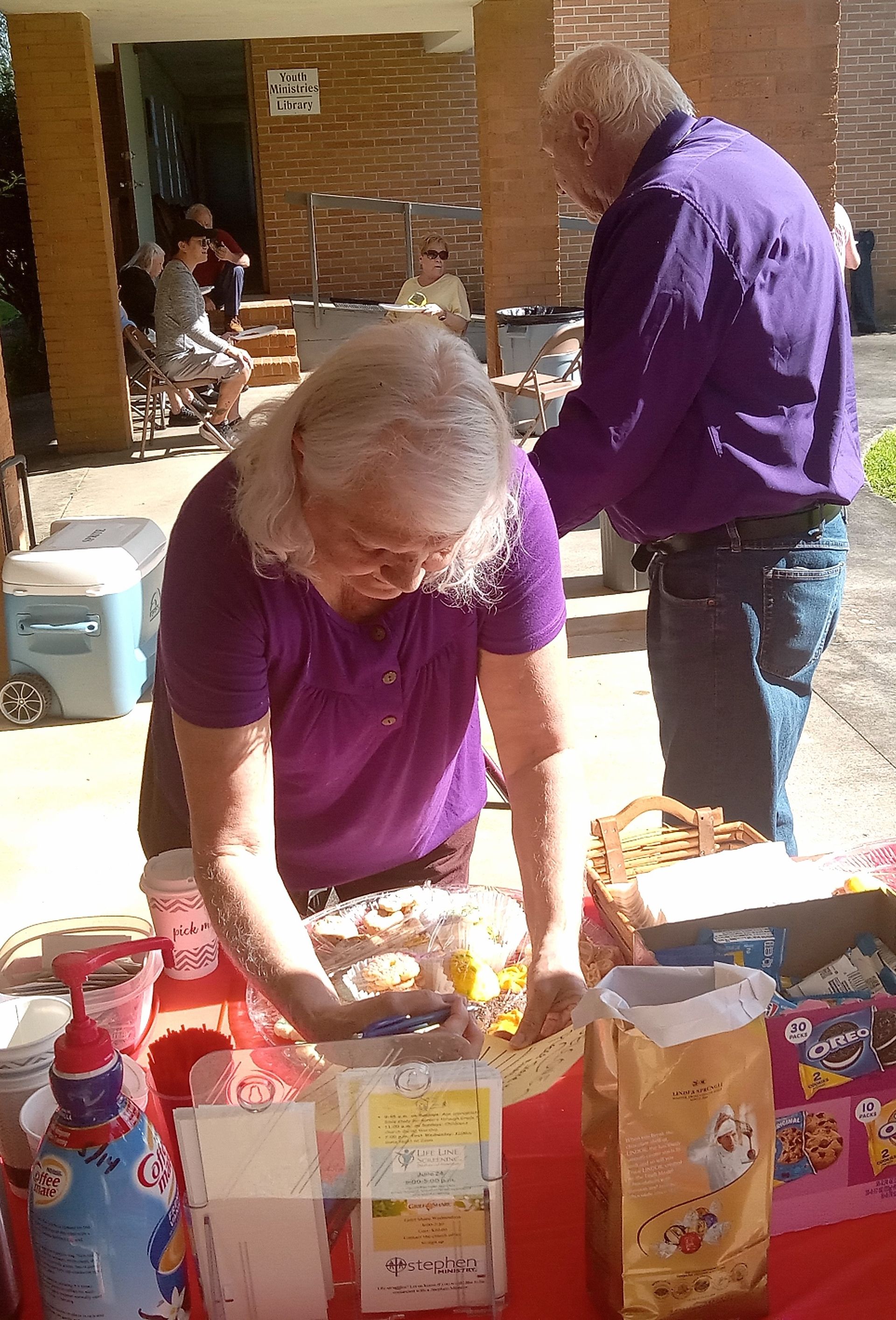 A man in a purple shirt is standing next to a woman in a purple shirt.