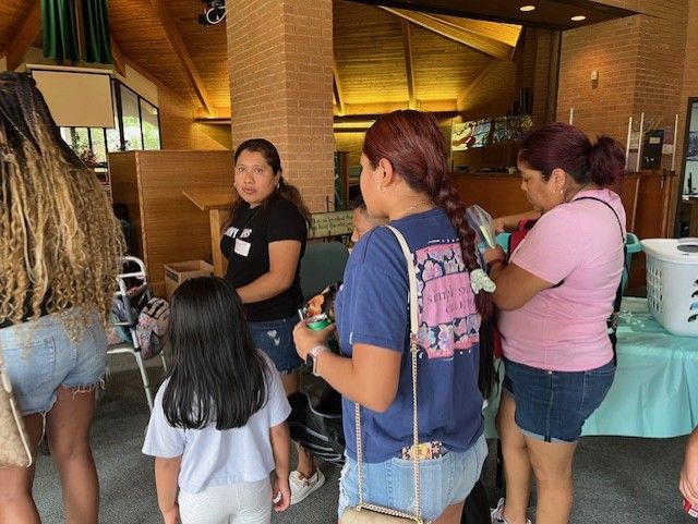 A group of women are standing around a table in a room.
