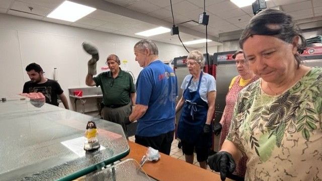 A group of people are standing around a counter in a kitchen.