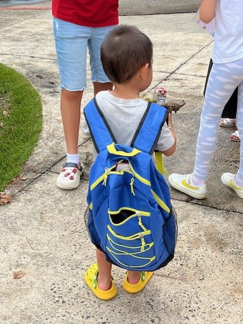 A little boy wearing a blue nike backpack