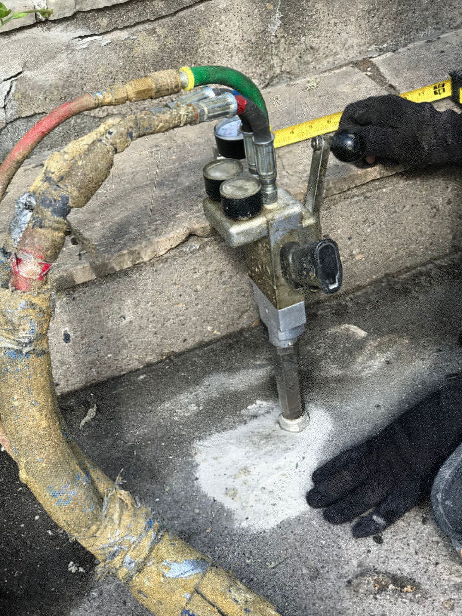 Concrete leveling equipment injecting material beneath uneven pavement.