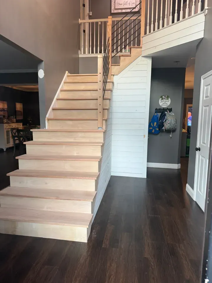 Interior staircase with light wood steps and railing in a modern home with dark hardwood floors.