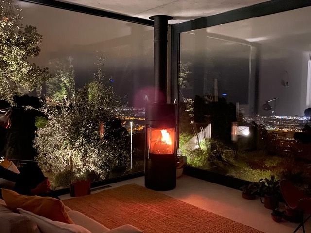 Una sala de estar con chimenea y un gran ventanal por la noche.