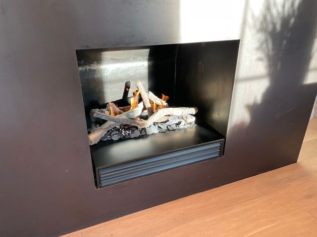 Una chimenea con muchos troncos en su interior se encuentra sobre un suelo de madera.