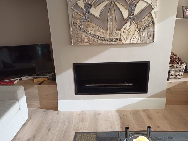 Una sala de estar con chimenea y un cuadro en la pared encima de ella.