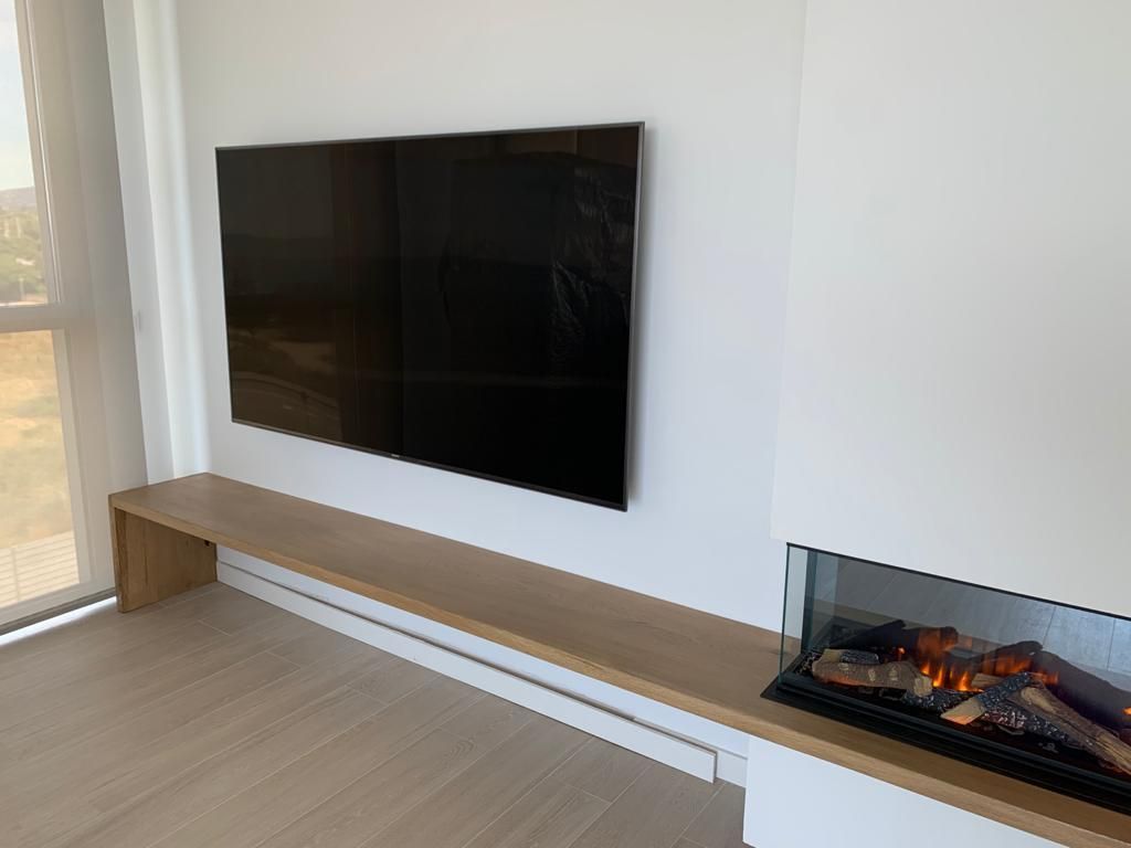 Una sala de estar con chimenea y un televisor de pantalla plana en la pared.