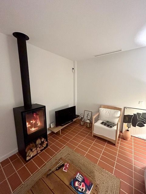Una sala de estar con chimenea, silla, mesa y televisión.