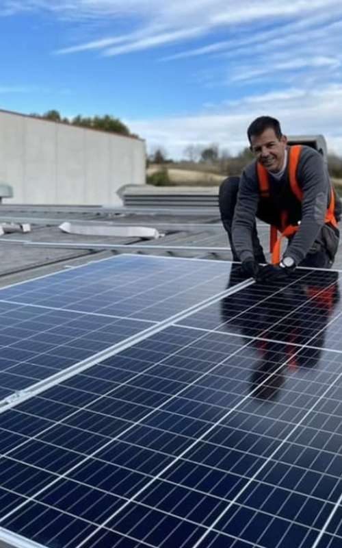 Un hombre está instalando paneles solares en el techo de un edificio.