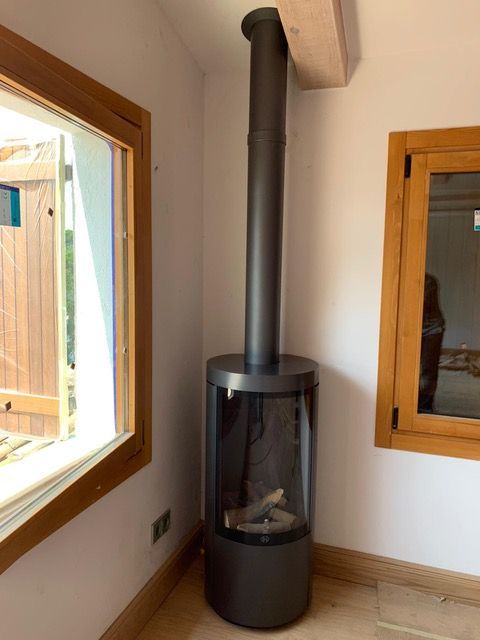 Una chimenea en un rincón de una habitación al lado de una ventana.