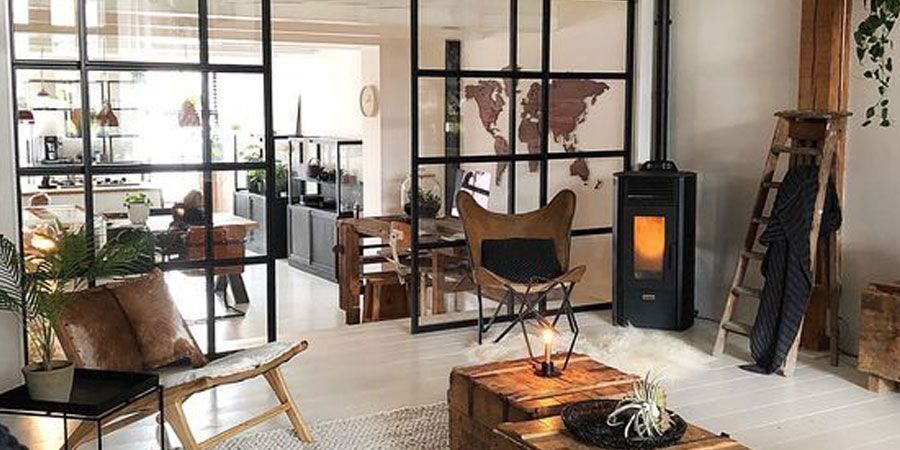 Una sala de estar con chimenea, sillas, una mesa y un mapa del mundo en la pared.