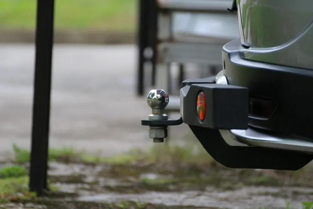 Silver car bumper with a trailer hitch ball and a black mounting bracket, with an orange reflector. — Hinterland Towbar & Steel Fabrication In Yandina, QLD