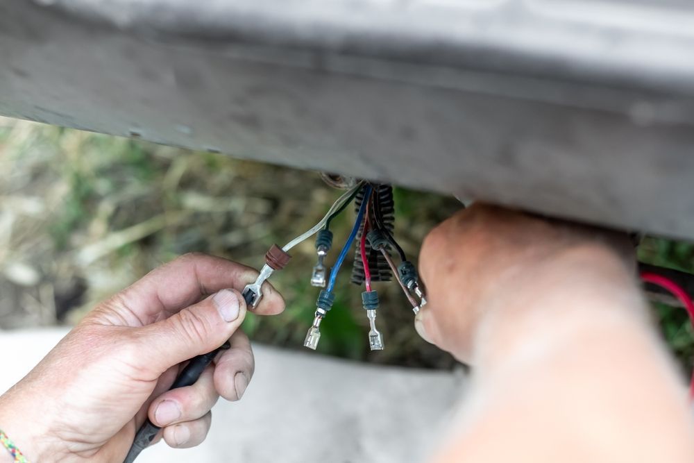 Person working with exposed electrical wires, possibly repairing them. — Hinterland Towbar & Steel Fabrication In Southside, QLD