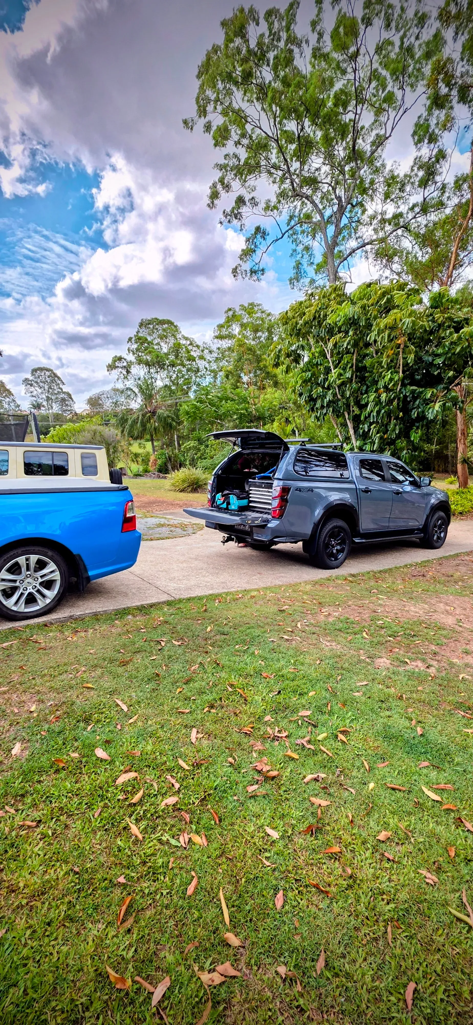 Two Pickup Trucks Parked on a Gravel Driveway Next to a Grassy Lawn — Hinterland Towbars in Southside, QLD