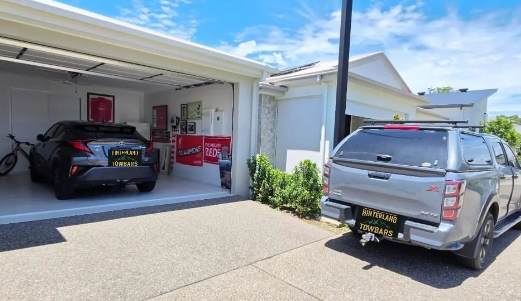 Garage With a Black Car and a Truck Parked Outside on a Sunny Day — Hinterland Towbar & Steel Fabrication