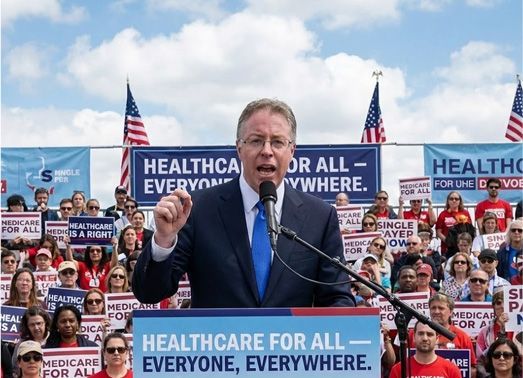 Man speaking at rally with signs advocating 