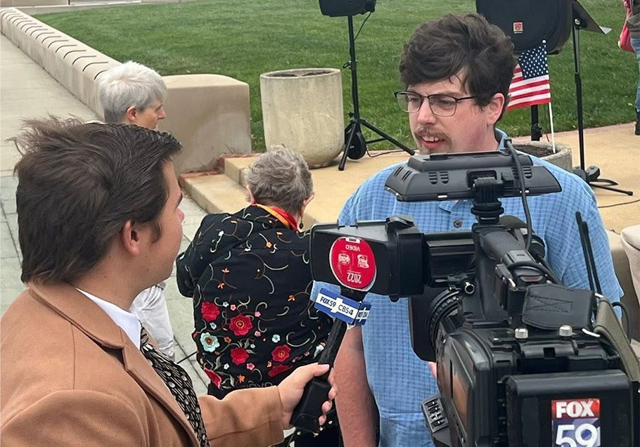 A tightly packed crowd of people in a sunny outdoor setting.