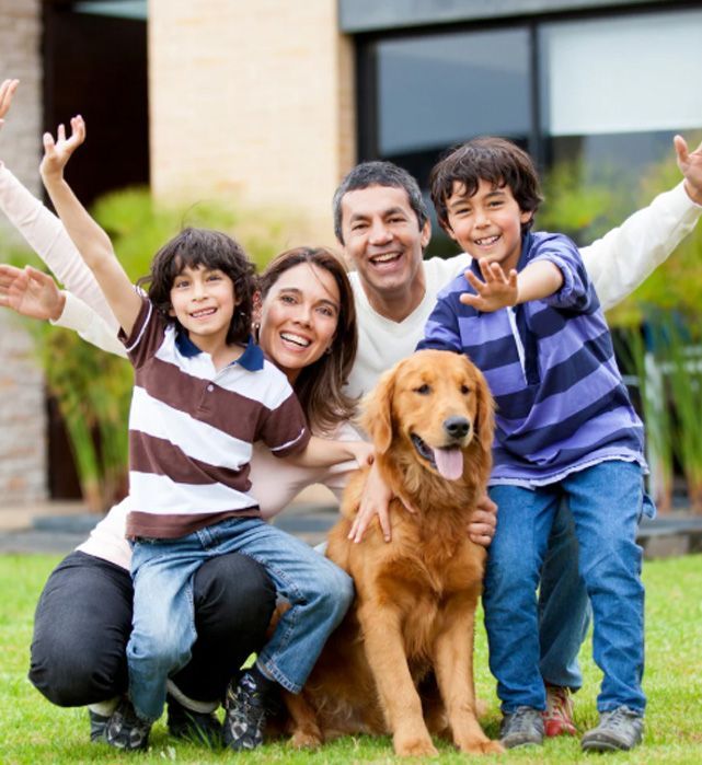 Family with two children and a golden retriever dog smiling and posing outside.