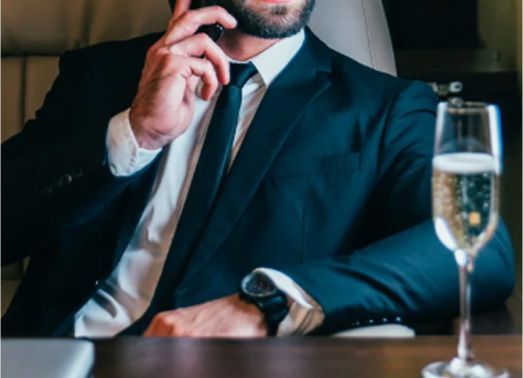 Man in suit on phone, champagne glass on table.
