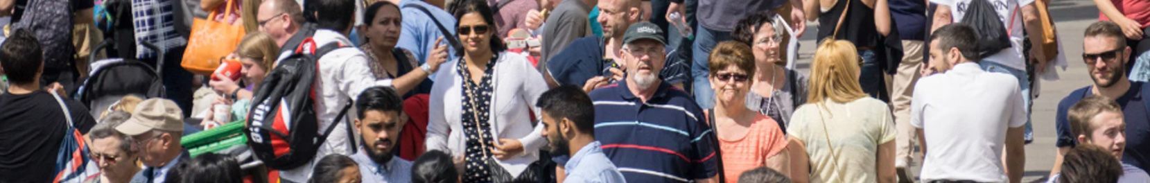 A tightly packed crowd of people in a sunny outdoor setting.
