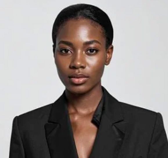Woman in a black blazer looking directly at the camera against a white background.