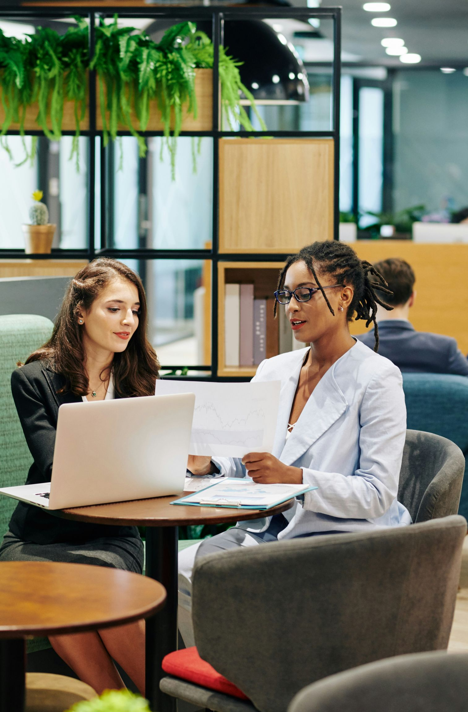 Woman in white shirt sits on a sofa, hands clasped. Reflection visible on a table.