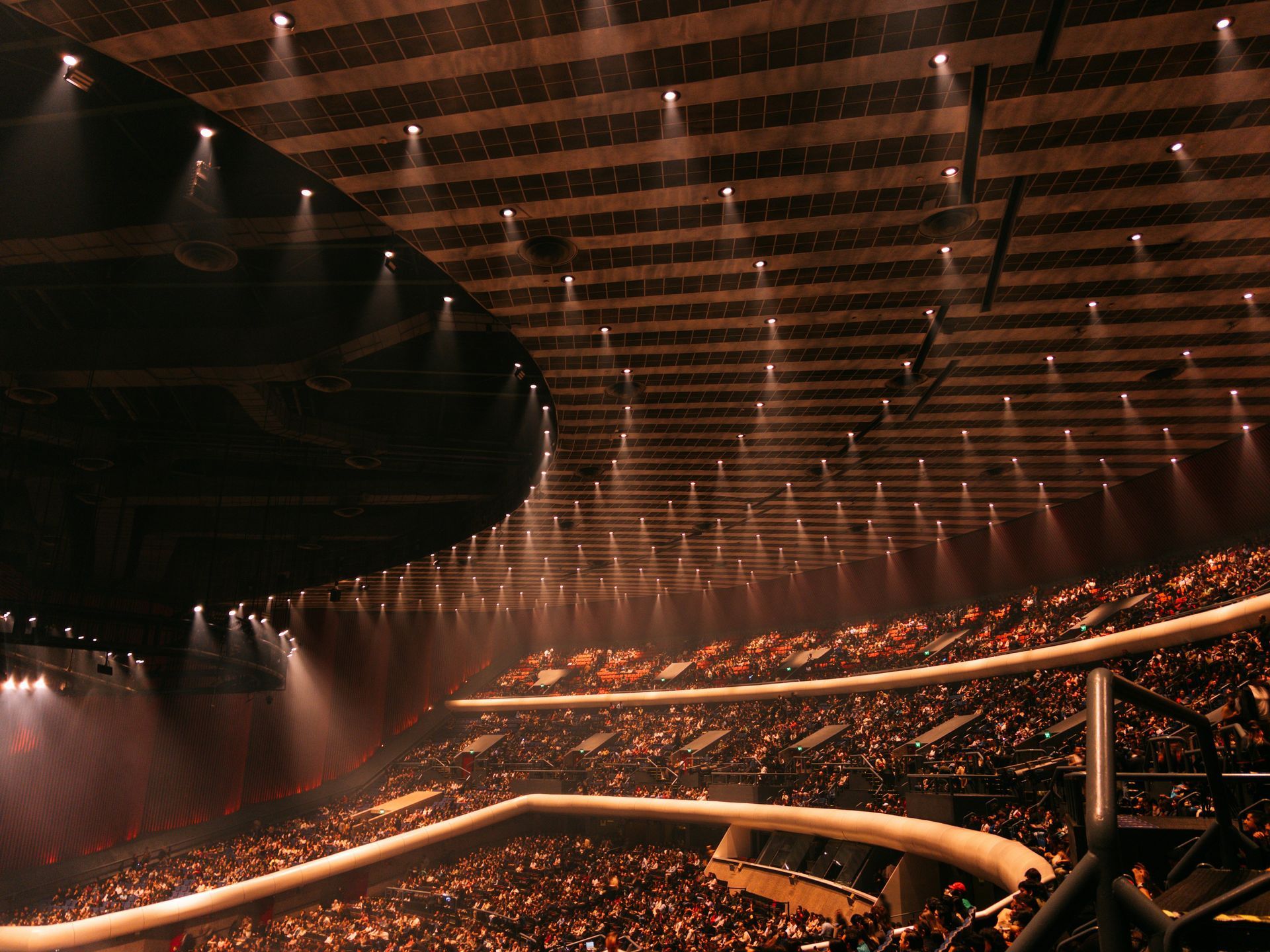 Woman in white shirt sits on a sofa, hands clasped. Reflection visible on a table.