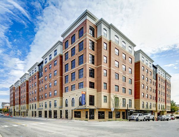 A large brick building with a lot of windows and cars parked in front of it.