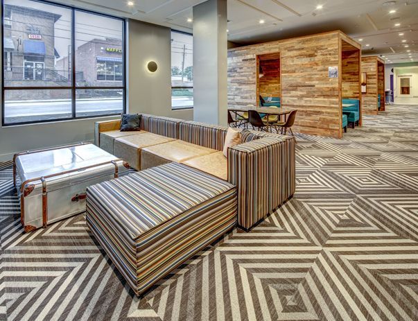 A living room with a couch , table and chairs in a hotel lobby.
