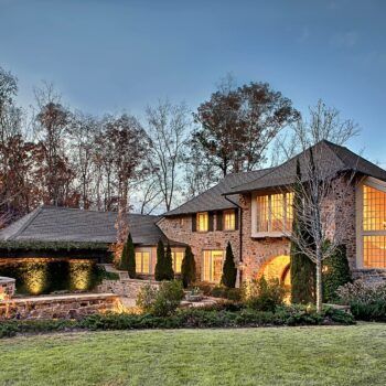 A large brick house with a lot of windows is lit up at night.