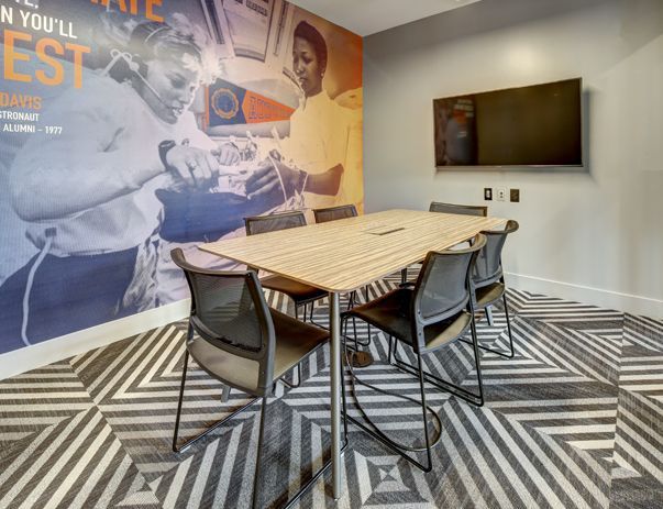 A conference room with a table and chairs and a television on the wall.
