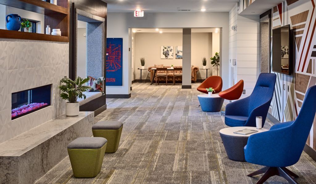 There are many chairs and tables in the lobby of a hotel.