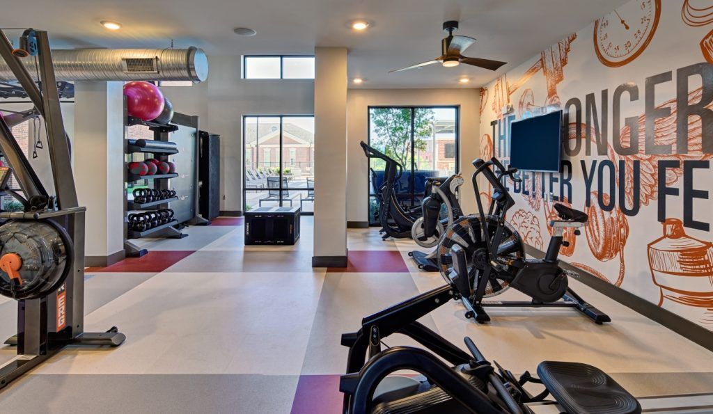 A gym with a mural on the wall that says `` stronger than you feel ''.