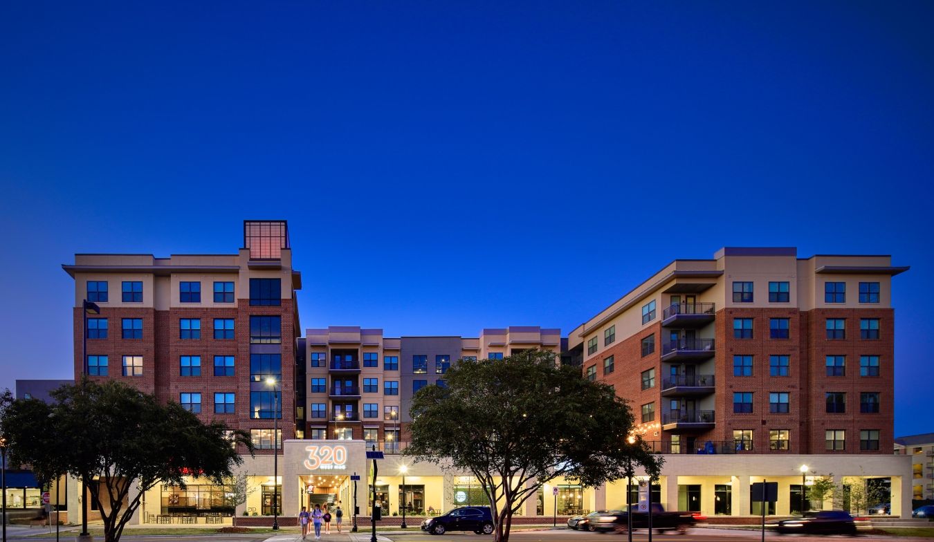 A large apartment building with a lot of windows is lit up at night.