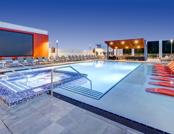A large swimming pool surrounded by chairs and a large screen.