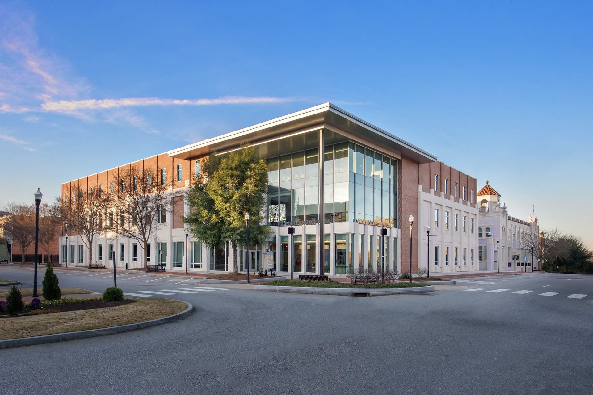 A large building with a lot of windows is sitting on the corner of a street.