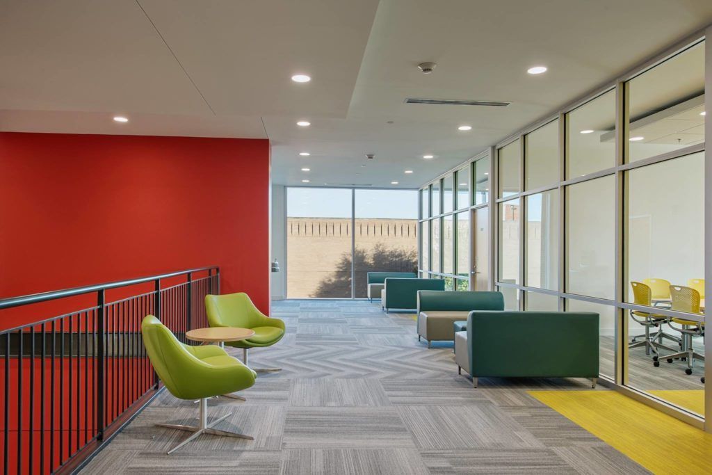 A hallway with green chairs and a red wall