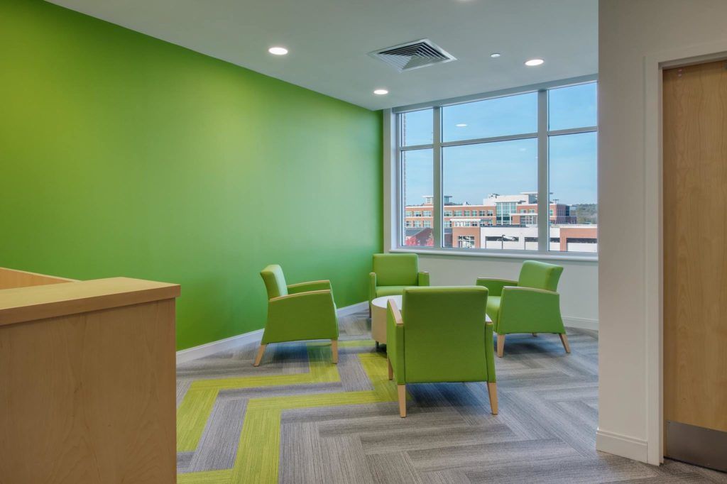 A living room with green chairs and a green wall.