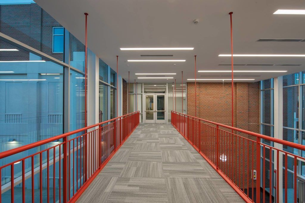 A long hallway with a red railing and a lot of windows.