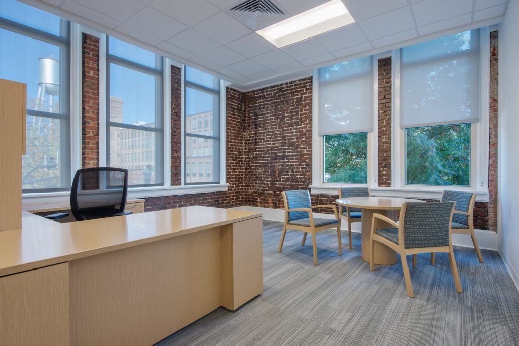 An empty office with a desk , chairs , and a table.
