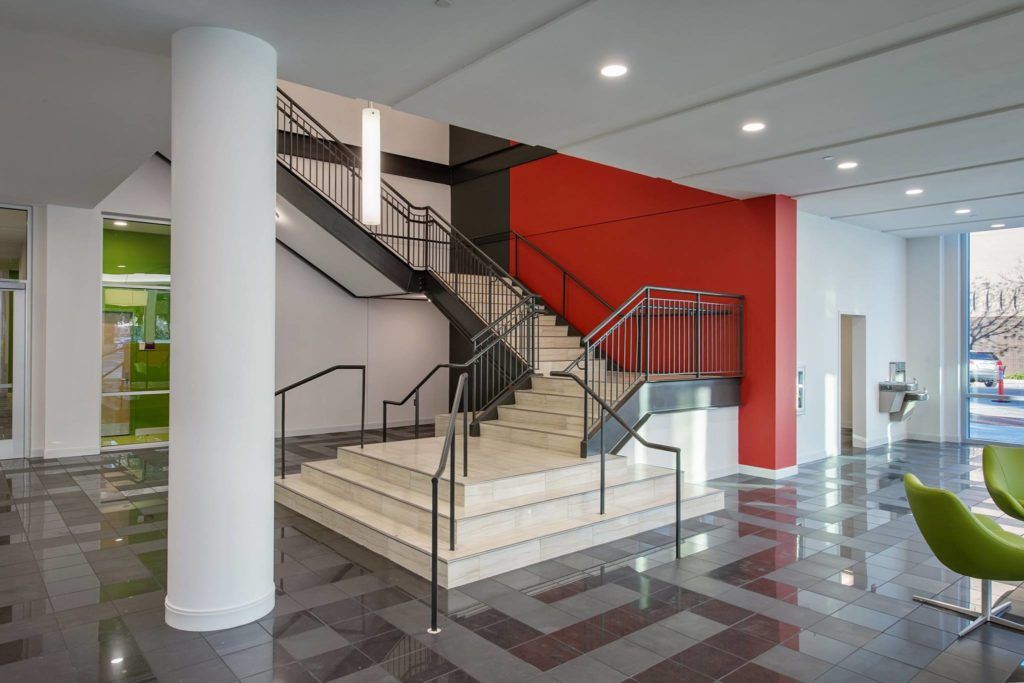 A lobby with stairs and a red wall