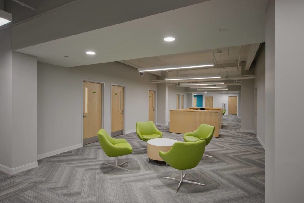 A rendering of a lobby with green chairs and a table.