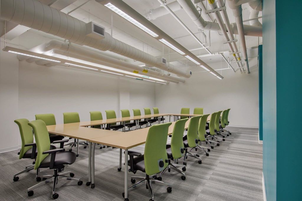 A conference room with a long table and green chairs.
