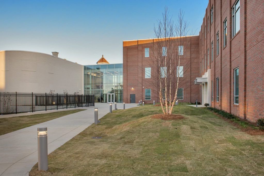 A large brick building with a lot of windows and a tree in front of it.