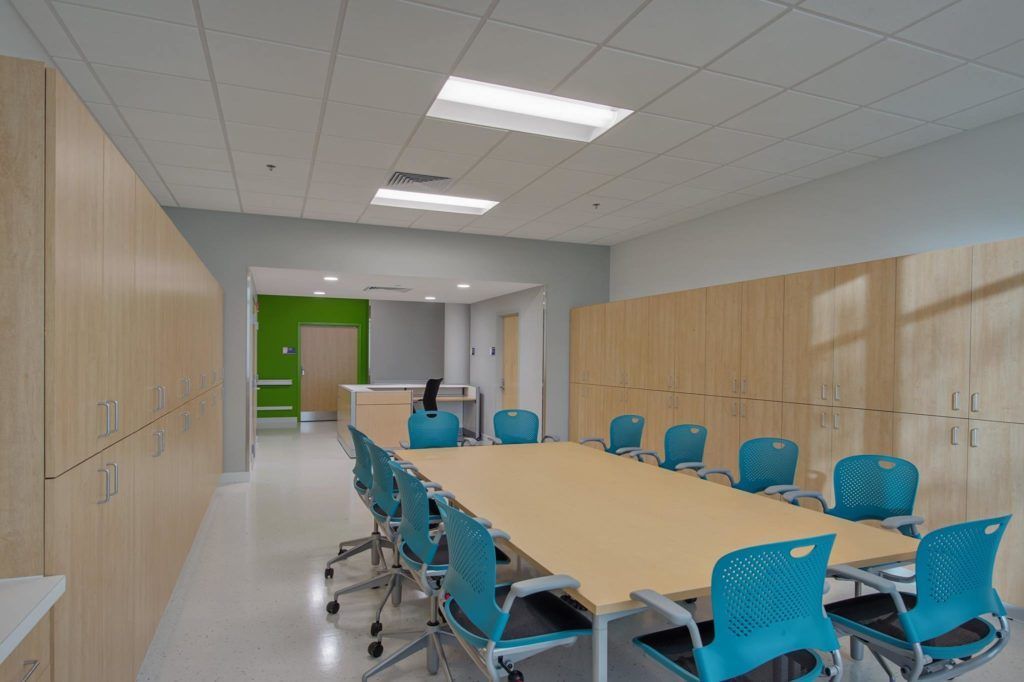 A conference room with a long table and blue chairs.