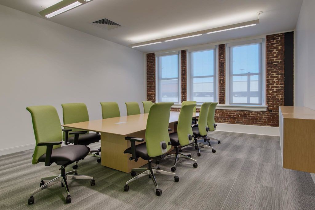 A conference room with a long table and green chairs