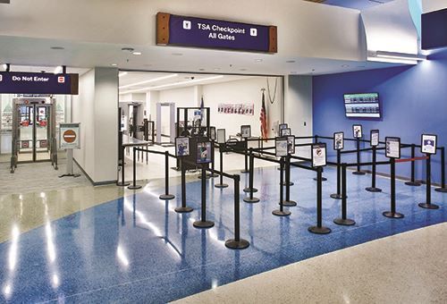 A row of barriers are lined up in a room at an airport.