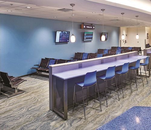 A waiting room with a long purple table and blue chairs