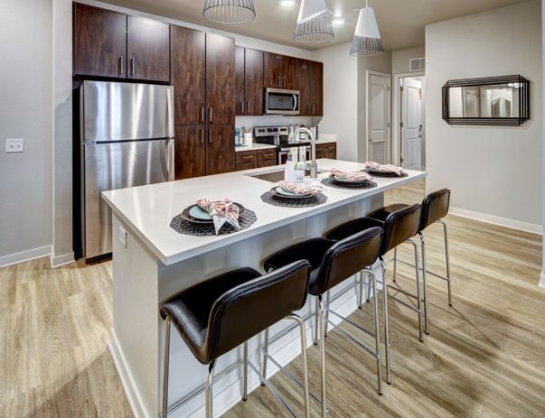 A kitchen with stainless steel appliances and a large island with stools.